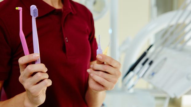 Woman dentist hands with tooth brushes. Closeup