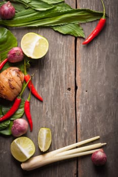 Ingredients set for Thai spicy soup (Tom-yum) include lemon, galangal, red chili, red onion, lemongrass, and kaffir lime leaf on wood table in morning scene with blank area for text or message