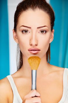 Portrait of a pretty young woman holding powder brush