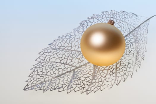 New Year background with golden glass toy on silver decorative leaf