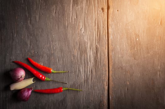 Thai spicy ingredients on wood background include red chili, red onion, and lemongrass in low key scene with blank copyspace area for text or message