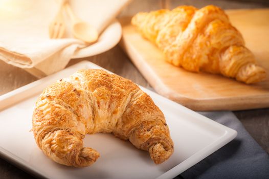 Whole wheat croissant on ceramic dish with morning scene
