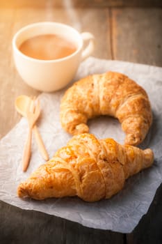 Butter croissant, whole wheat croissant, and a cup of hot chocolate on wood table with morning scene