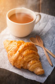 Butter croissant with a cup of hot chocolate on wood table with morning scene