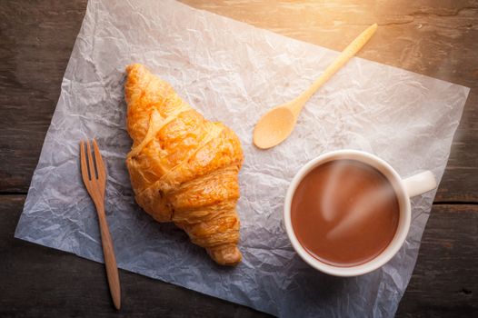 Butter croissant with a cup of hot chocolate on wood table with morning scene