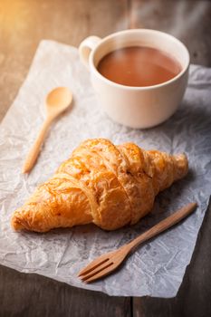 Butter croissant with a cup of hot chocolate on wood table with morning scene