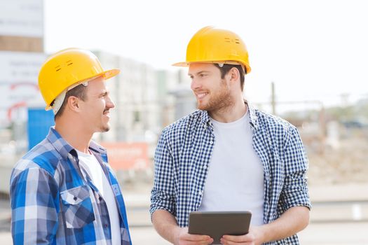 business, building, teamwork, technology and people concept - group of smiling builders in hardhats with tablet pc computer outdoors