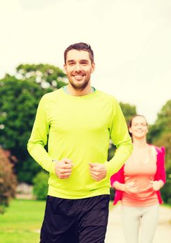 fitness, sport, friendship and lifestyle concept - smiling couple running outdoors