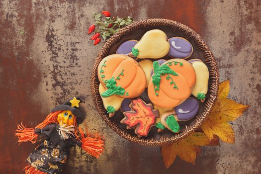 Decorated cookies and witch on rustic table