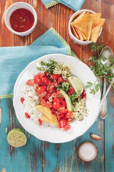 Pico de gallo and nacho chips on rustic wooden table background. Natural light