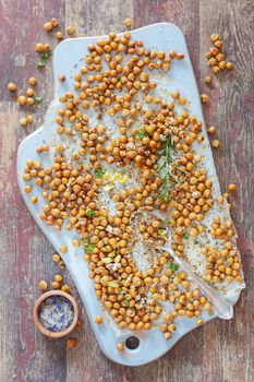 Spicy Oven Roasted Chickpeas on a wooden board, rustic wooden background, vintage style. Natural light