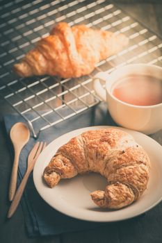 Butter croissant and whole wheat croissant with a cup of hot chocolate on wood table in morning time with film filter effect