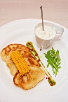 corn pancakes with cream at plate