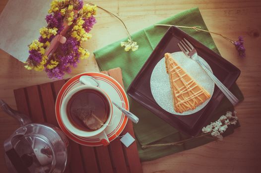 Top view of Thai tea cake on black ceramic dish with a cup of hot tea in morning time with film filter effect