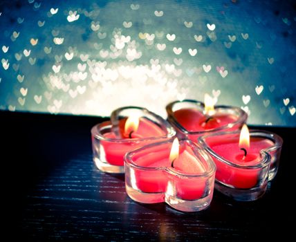red burning heart shaped candles on blue hearts bokeh background