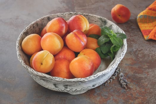 Bowl of harvested apricots on a rustic stone surface, top view, rustic style. Natural light
