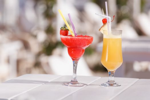 Cocktails garnished with fruit and flowers outdoors. Selective focus