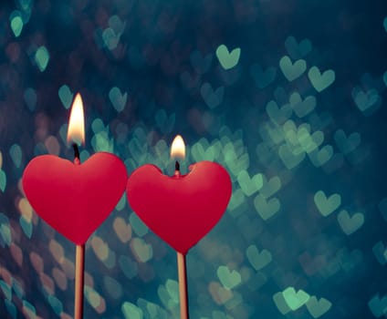 red hearts candles on vintage hearts bokeh as background, valentine day and love concept