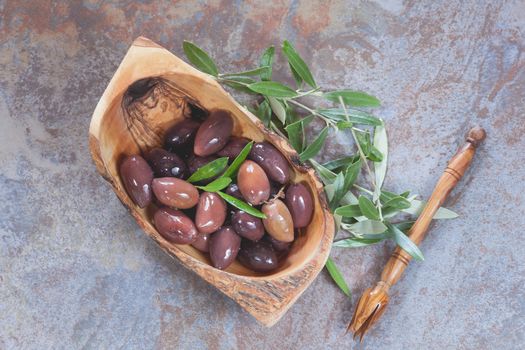 Mixed oily olives in olive wood bowl and olive sprig..Macro, selective focus, copy space, top view