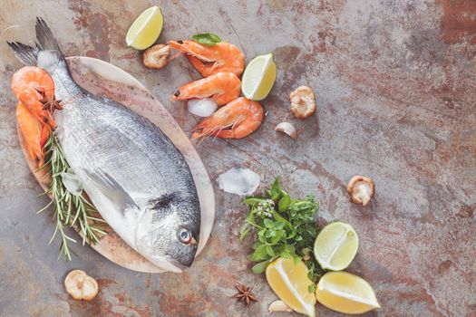 Sea bream, shrimp and fresh raw ingredients ready for cooking, top view