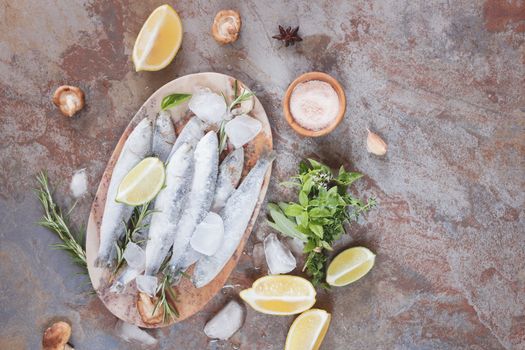 Frozen sardines. High angle view of frozen fish decorated with lemon and herbs on plate.