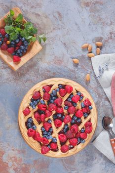 Whole homemade mixed berry lattice top pie on rustic table, top view