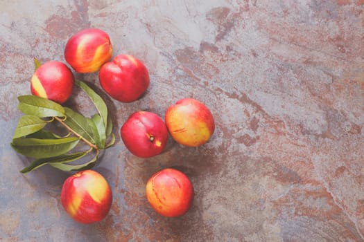 Nectarines. Couple of fresh wet nectarines and sprig of nectarine leaves on rustic table, top view