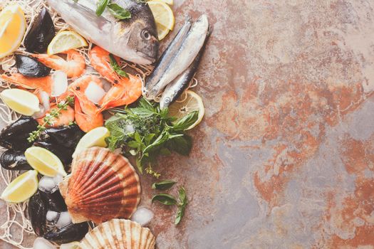 Overhead shot of raw scallops, fish, shrimps and mussels with lemon and spices on crushed ice. Preparing food concept