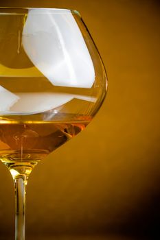 white wine into a glass on golden background with space for text, warm atmosphere