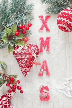 Christmas background with woolly Christmas decorations and XMAS letters on rustic wood background.