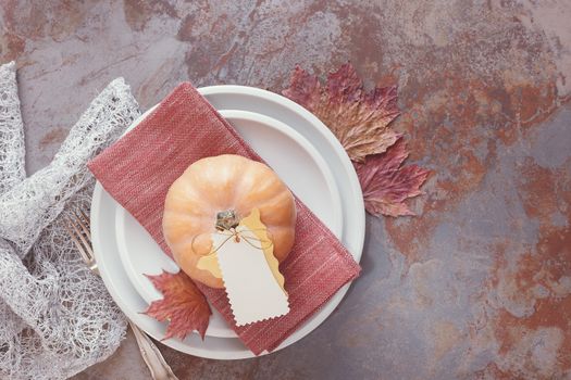 White plates decorated with pumpkin, autumn leaves and placard. Thanksgiving Table Decorations