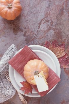 White plates decorated with pumpkin, autumn leaves and placard. Thanksgiving Table Decorations