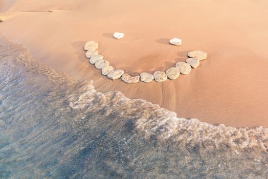 Emoticon of pebbles on the sandy seashore