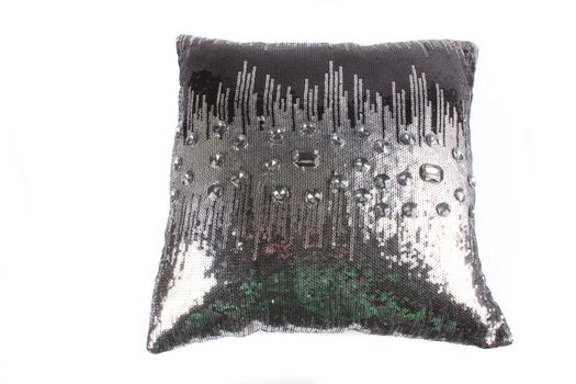 A luxurious pillow with a design of sliver sequins and glass beads, on white studio background