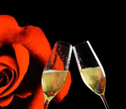 champagne flutes with golden bubbles make cheers on rose flowers and black background, wedding and valentine day concept