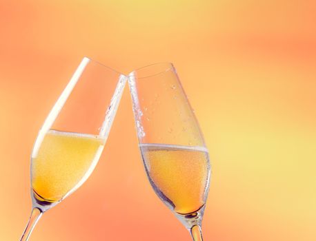 two flutes of champagne with golden bubbles and space for text on golden background