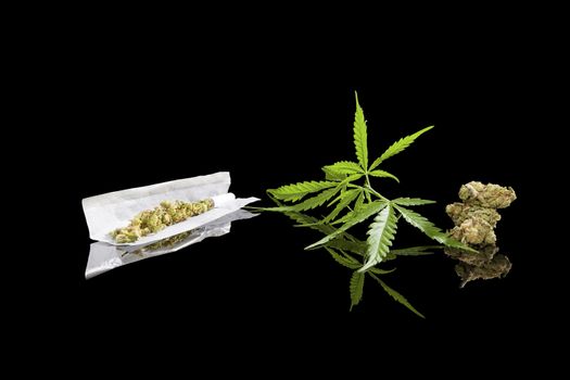 Marijuana background. Cannabis cigarette joint, bud and hemp leaves isolated on black background. Addictive drug or alternative medicine. 