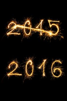 Strikethrough 2015 and 2015 digits made of sparkling light isolated on black background. Old year going, new year comming.