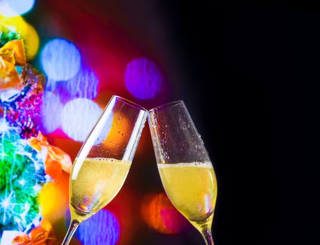 champagne flutes with golden bubbles make cheers on christmas lights bokeh decoration background, christmas atmosphere