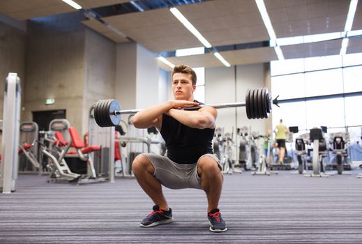 sport, bodybuilding, lifestyle and people concept - young man with barbell doing squats in gym