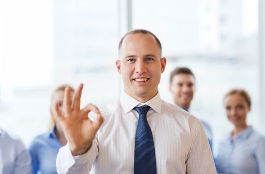 business, people, gesture and teamwork concept - smiling businessman showing ok sign with group of businesspeople in office