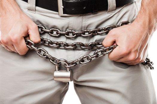 Sexual issues and forbidden sex concept - man hands holding padlock locked metal chain chastity belt over pants or jeans zip fly