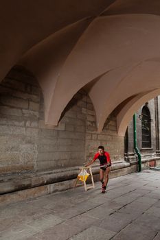 Man punching at control point, taking part in orienteering city race competitions in old european city