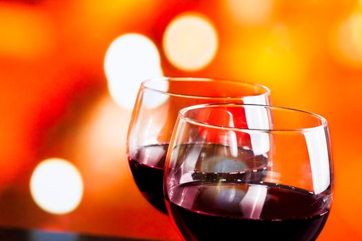 red wine glasses against colorful unfocused lights background, festive and fun concept