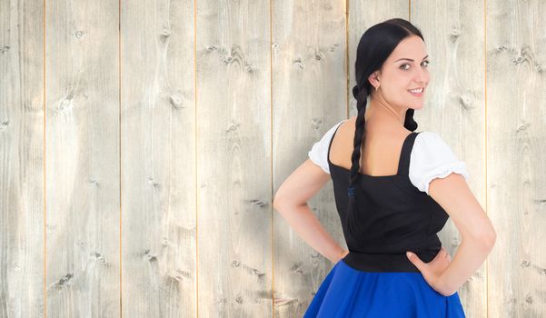 Pretty oktoberfest girl smiling at camera against pale wooden planks