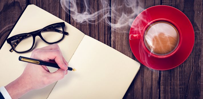 Overhead view of hot tea by hand writing on book against wooden table