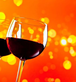 two red wine glasses against golden bokeh lights background, festive and fun concept