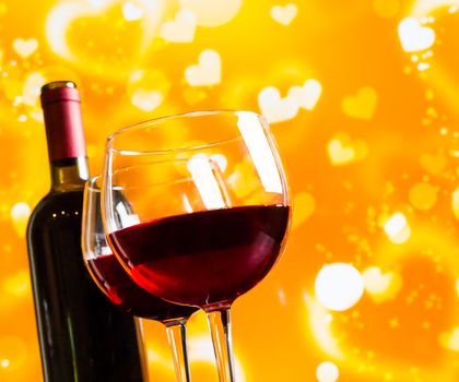 two red wine glasses against golden hearts bokeh lights background, festive and love concept