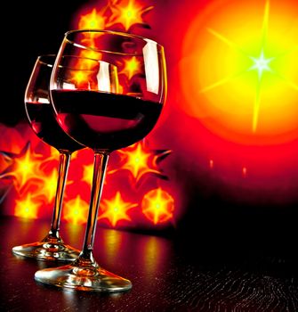 two red wine glass against golden lights tree background, christmas atmosphere