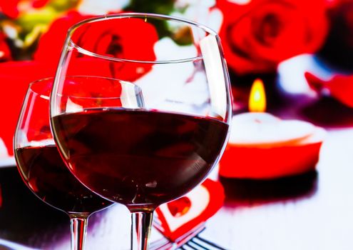 two red wine glasses on blur hearts and roses decoration background, festive and love concept